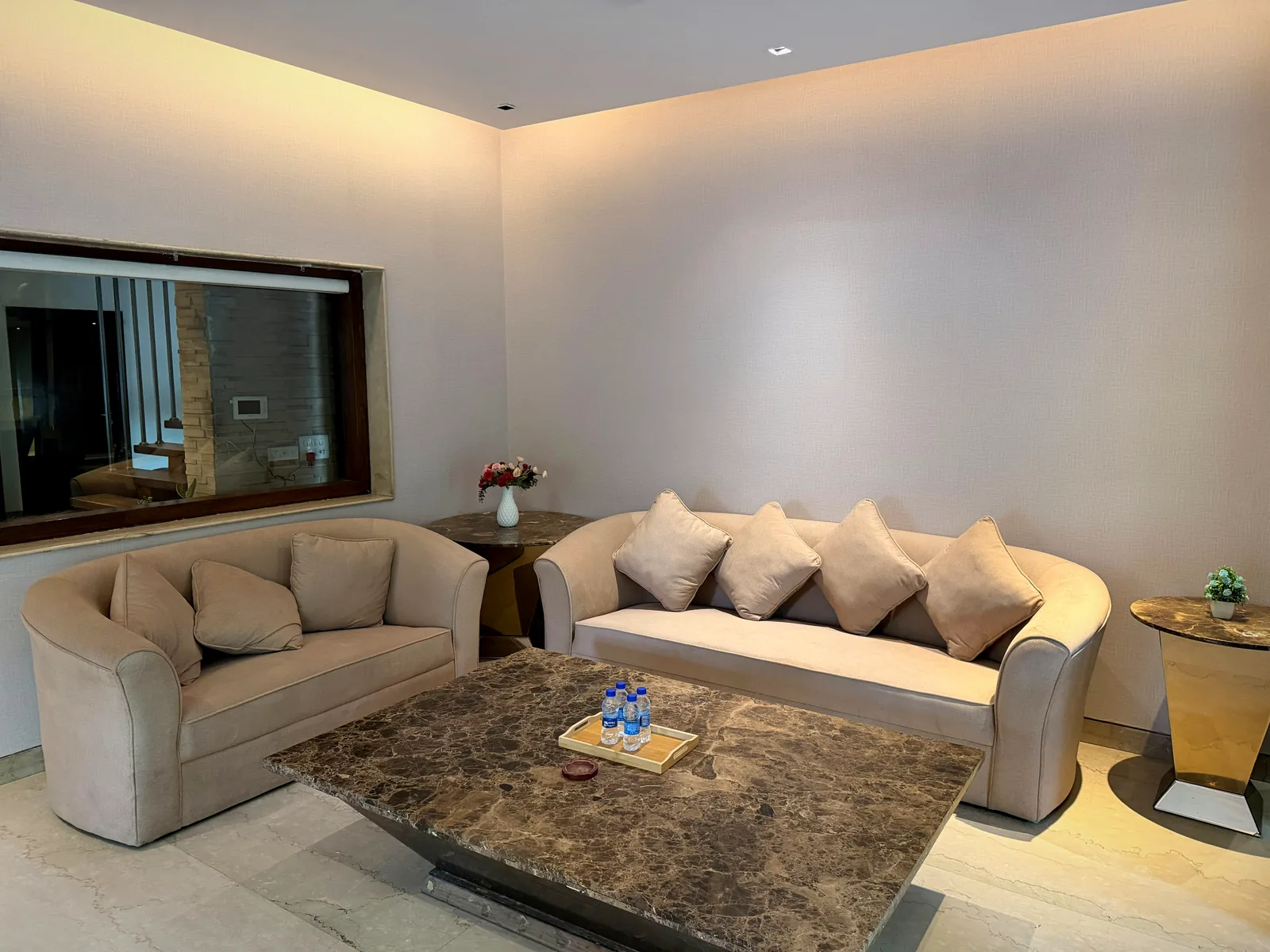 Beige sofas around a marble coffee table in the living room of the 5 BHK villa in Gurgaon