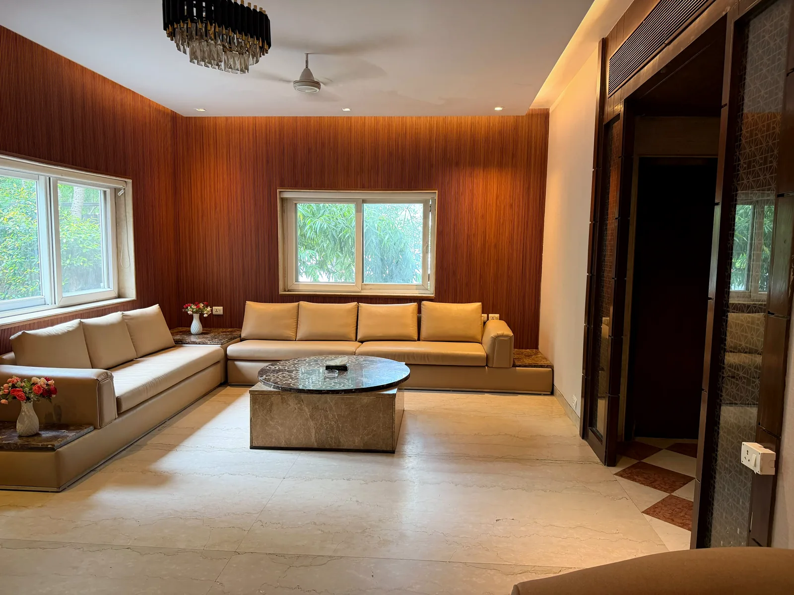 Family lounge with wood-panelled walls and garden windows at Nivasa Villas, Gurugram